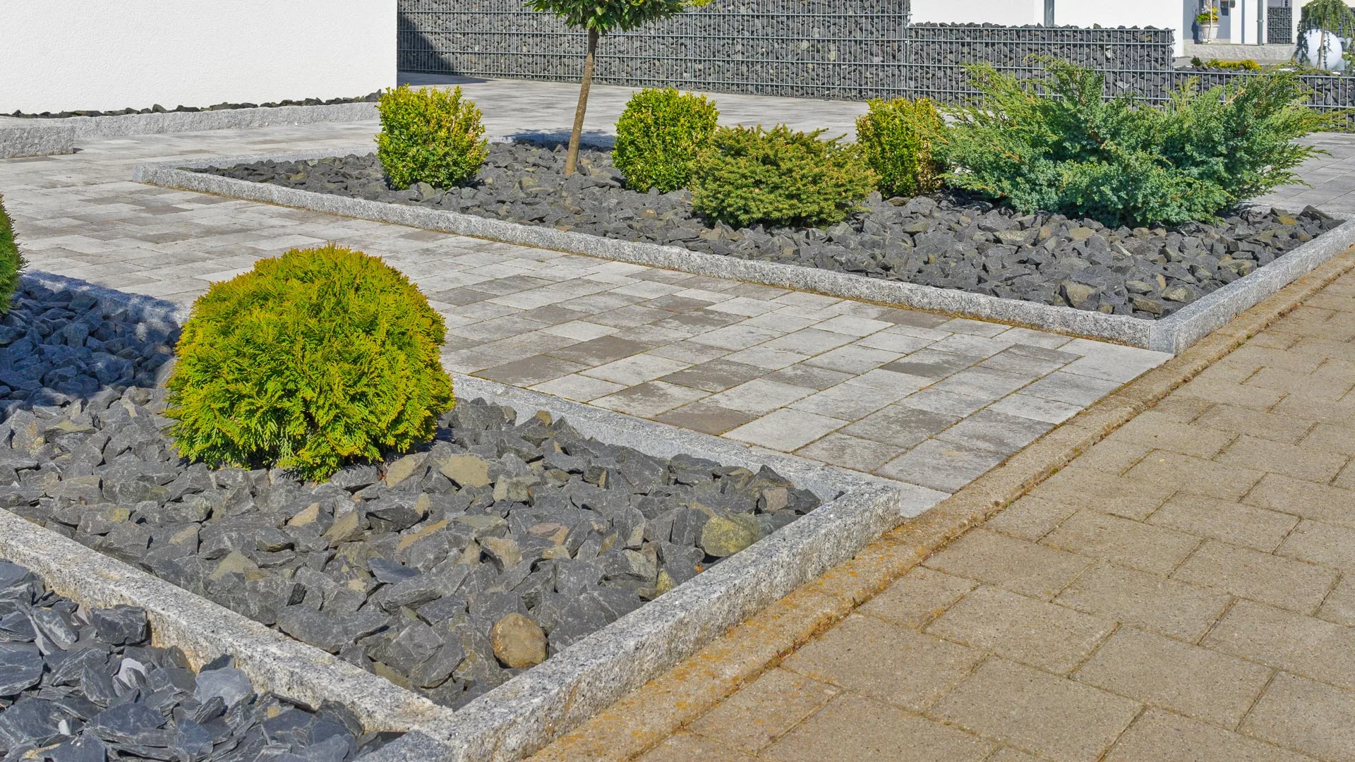 A paver side walk with decorative rock accents and small shrubs outside a commercial building in Bethlehem, %%sate%%.